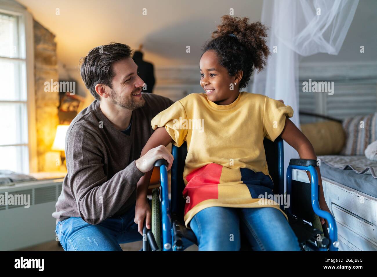 Happy multiethnic family. Smiling little girl with disability in wheelchair Stock Photo