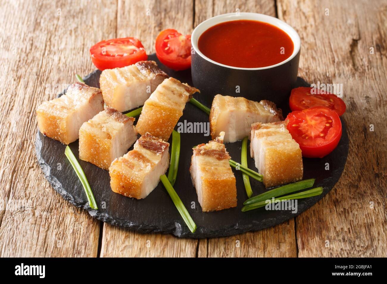 Filipino Crispy Fried Pork Belly Lechon Kawali closeup in the slate dish on the table. Horizontal Stock Photo