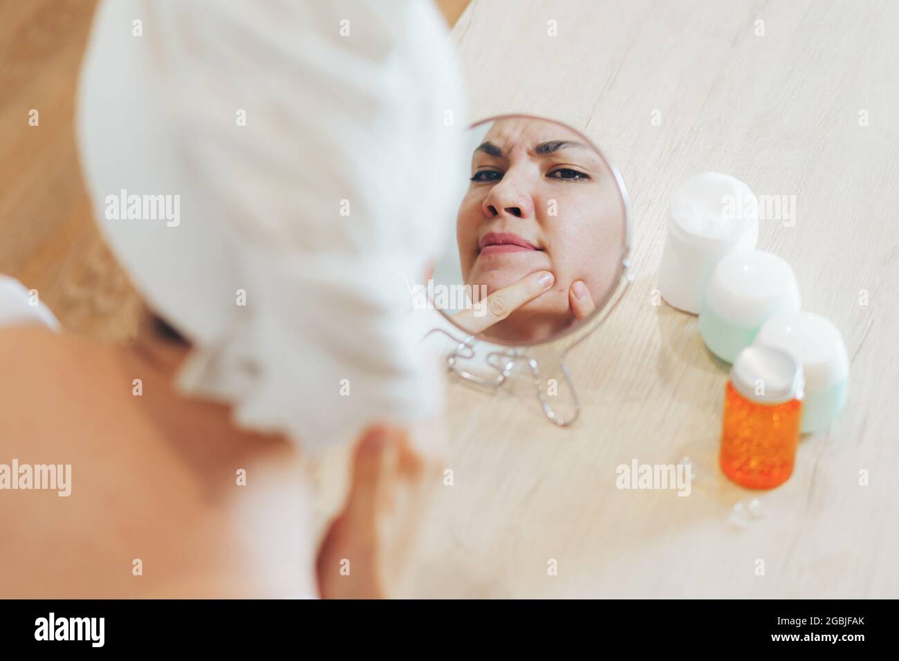 Young girl presses pimples and blackheads on her face. Stock Photo