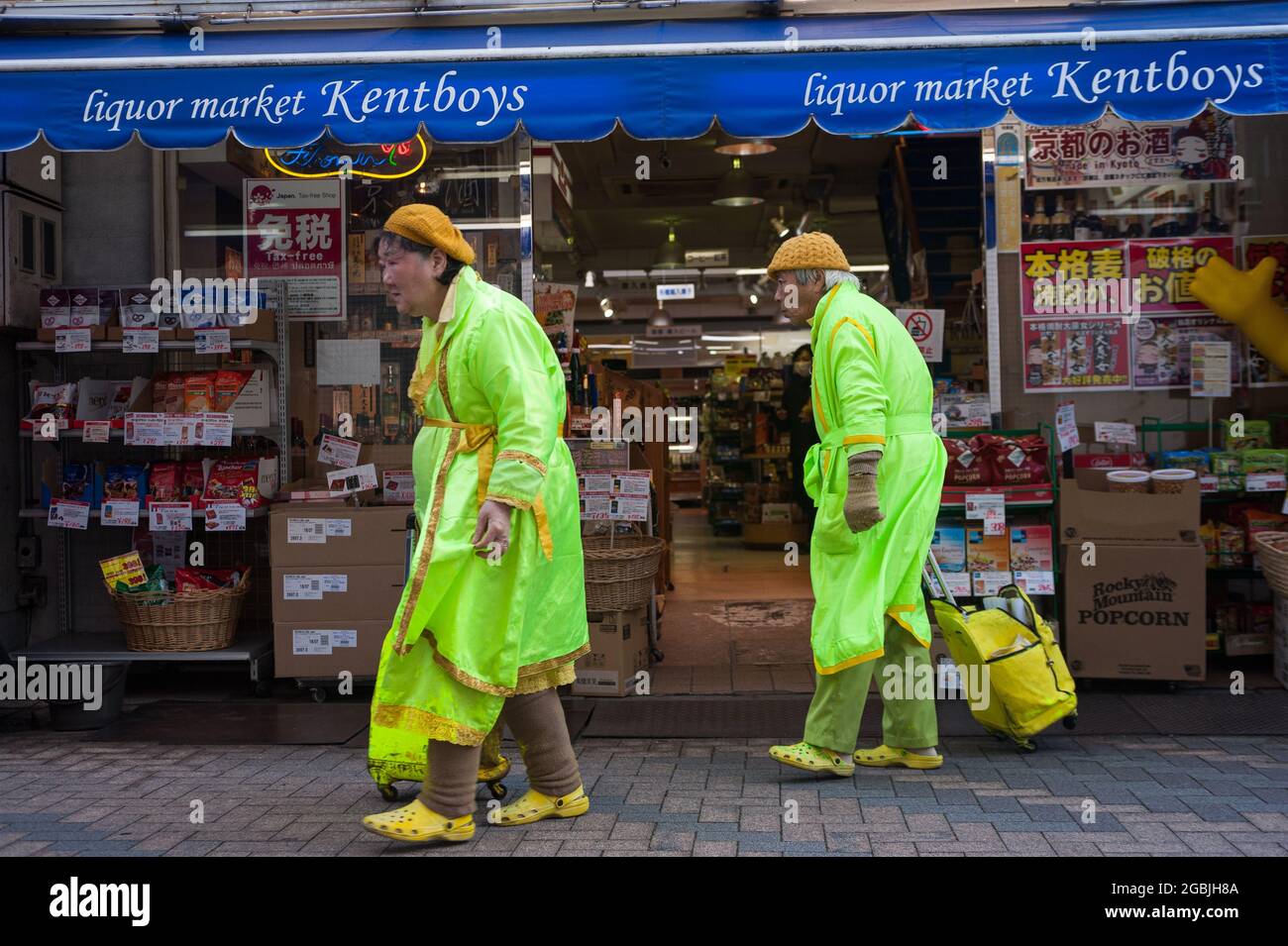 25.12.2017, Kyoto, Japan, Asia - An elderly couple wearing bright matching outfits in front of a liquor market in the city centre. Stock Photo