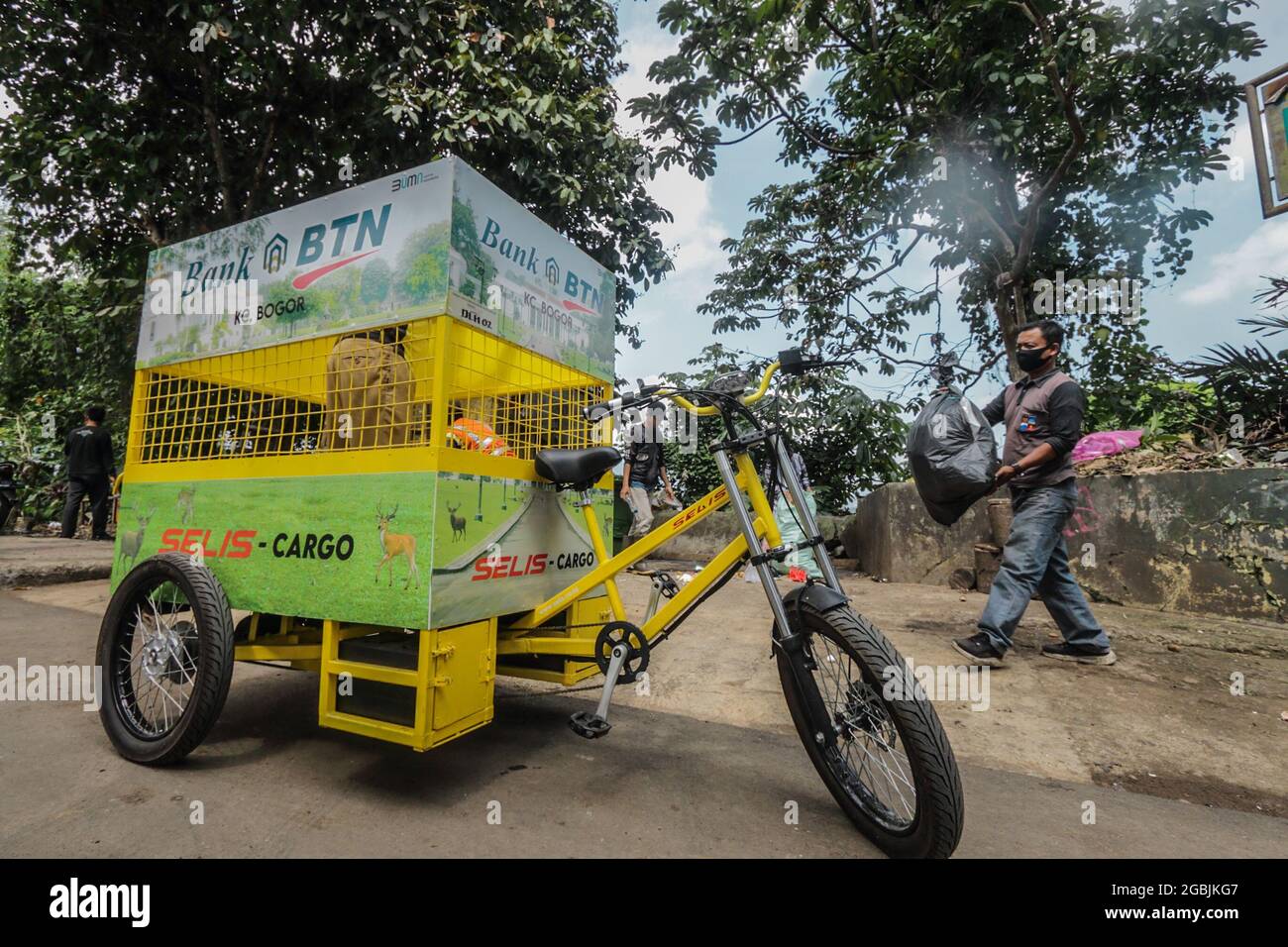 An officer carry a garbage bag into an electric bicycle that transports non-organic waste on a road in Bogor, West Java, Indonesia, on August 4, 2021. The electric bicycle that carries waste that does not emit exhaust gas emissions and is more environmentally friendly can cover a distance of 25 km and has a capacity of 200 kilograms to accommodate non-organic waste. (Photo by Andi M. Ridwan/INA Photo Agency/Sipa USA) Stock Photo