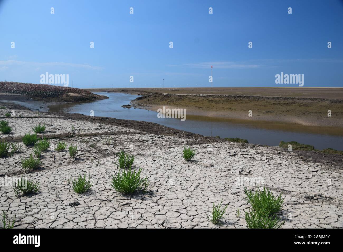 The tide is out on the Mersey estuary shore showing exposed sand banks, sea birds, river Alt tributary under blue sky's and summer sunlight. Stock Photo