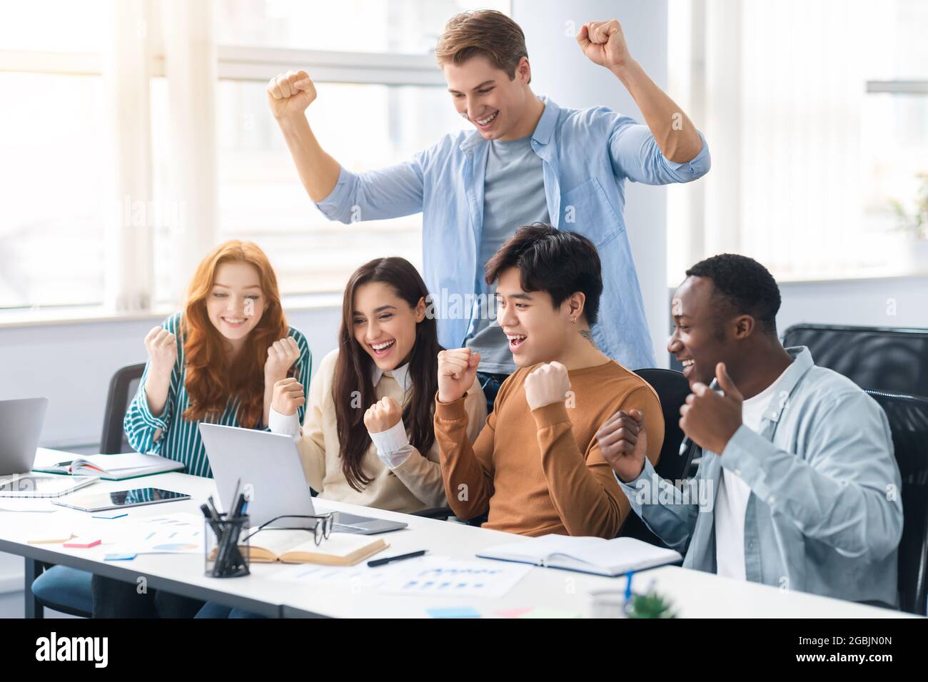 Group of international people using laptop and shaking clenched fists Stock Photo