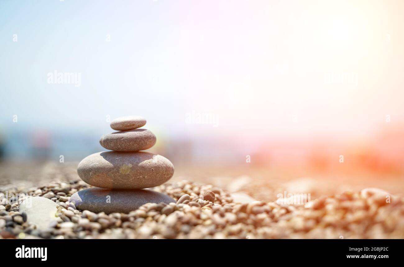 Zen stones are background. A pyramid of pebble stones against the background of the sky, sea and beach. Meditation, yoga, calming the mind and relaxation concept. High quality photo Stock Photo