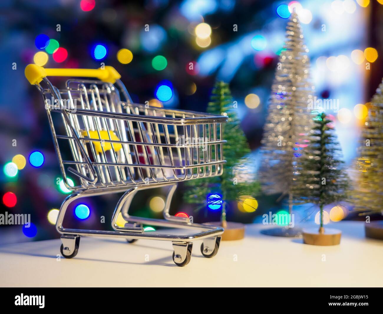 empty small shopping cart on a festive christmas tree background Stock Photo