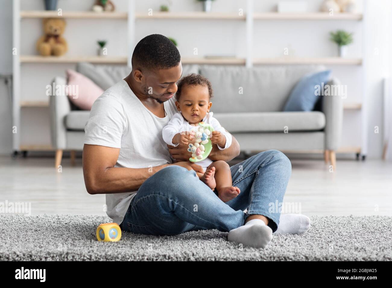 Fatherhood Concept. Happy Black Man Playing With Adorable Infant Child At Home Stock Photo
