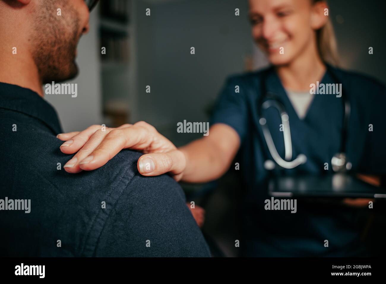 Caucasian female nurse holding shoulder of male patient Stock Photo