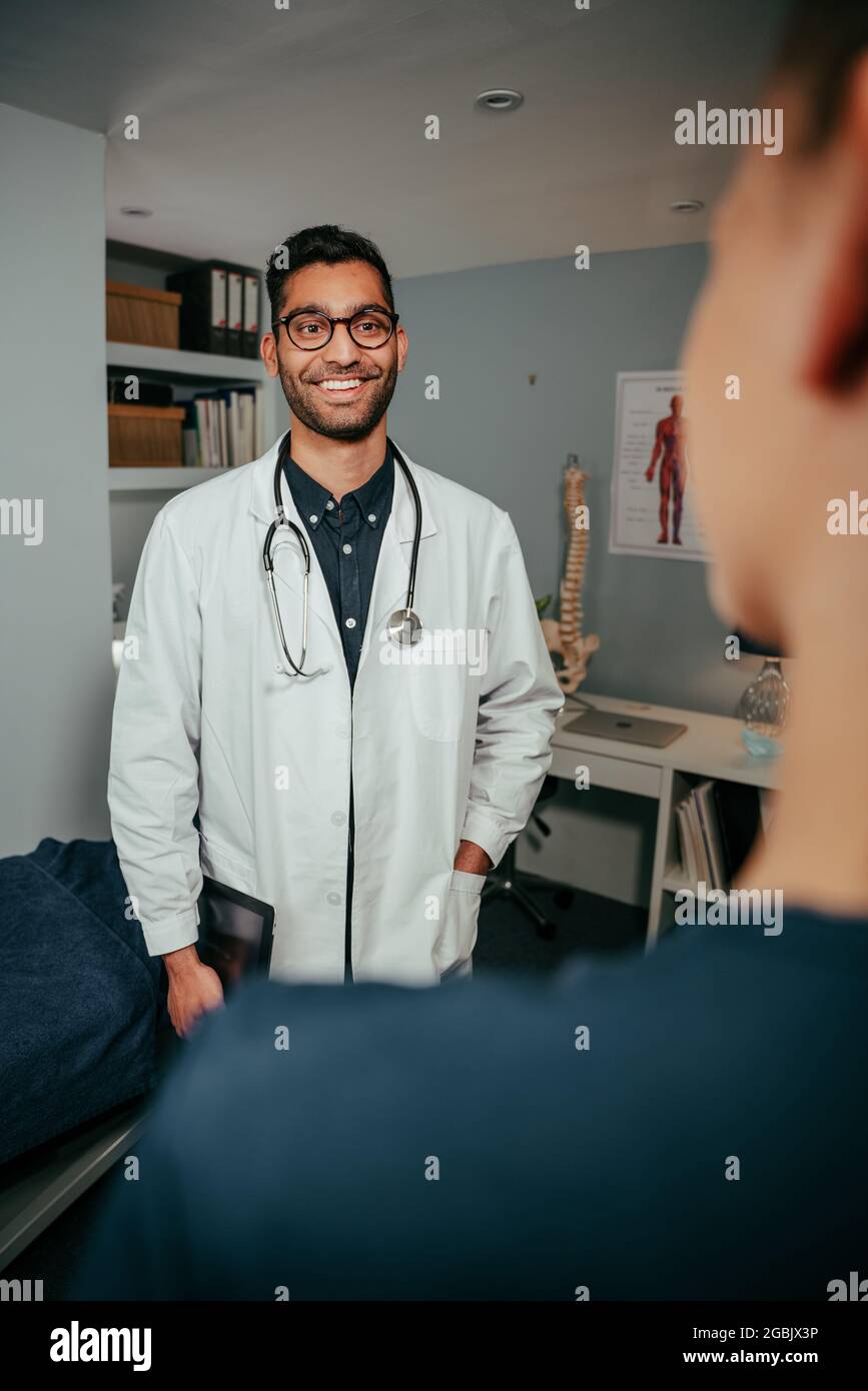 Mixed race male nurse standing smiling while chatting to female doctor Stock Photo