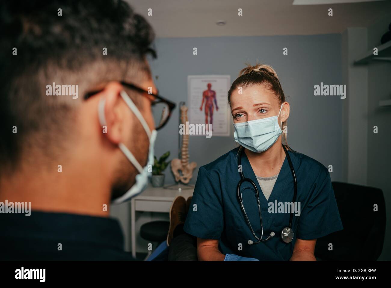 mixed race male patient standing with female nurse in doctors office Stock Photo