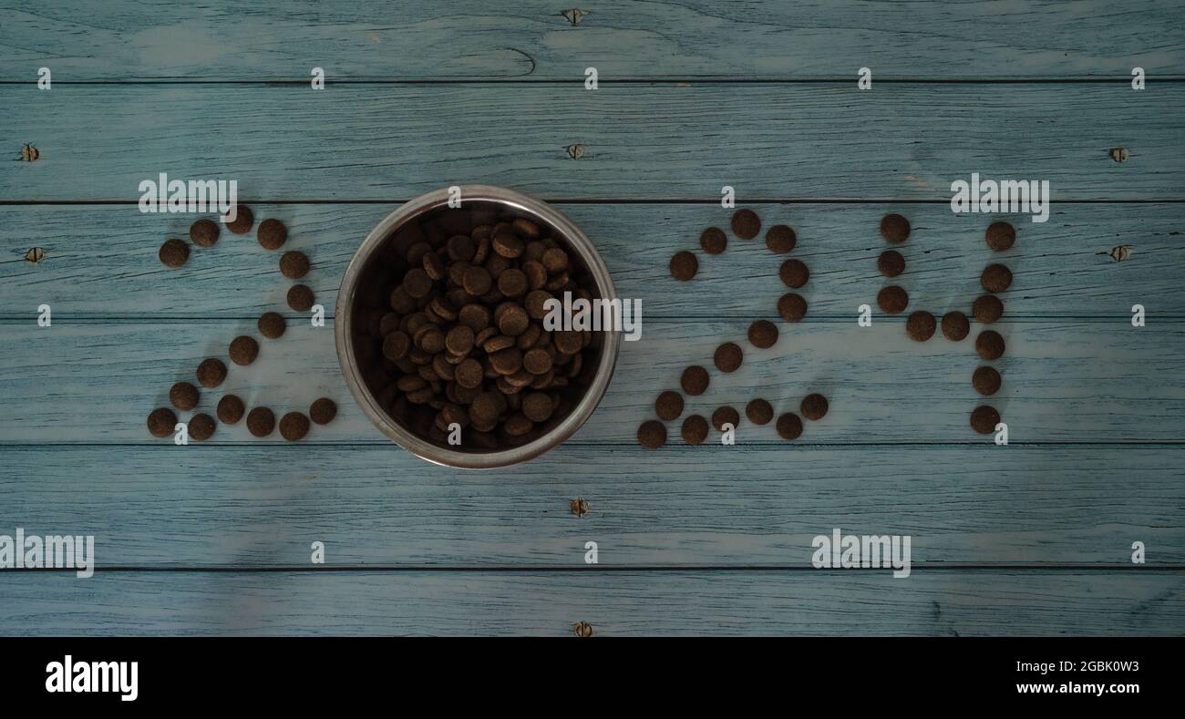 New Year or Christmas concept minimalistic background with the numbers 2024 from cat or dog food. Creative advertising of a pet store. Blue wooden tab Stock Photo