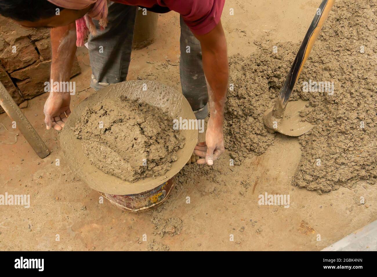 Indian construction labour mixing cement and water manually on floor