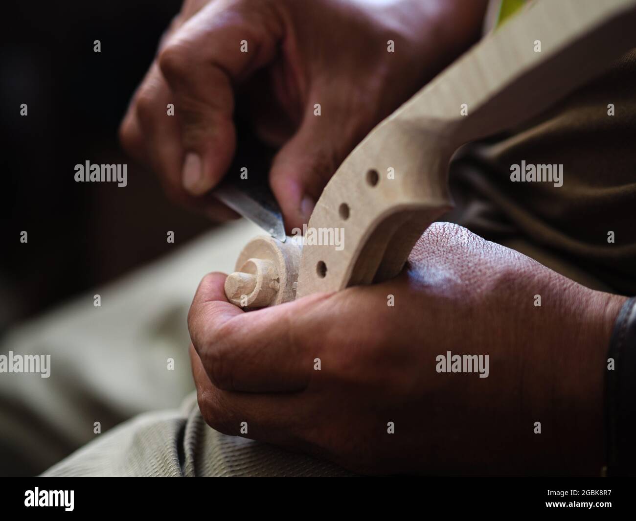 Luthier working on violin head and curl Stock Photo