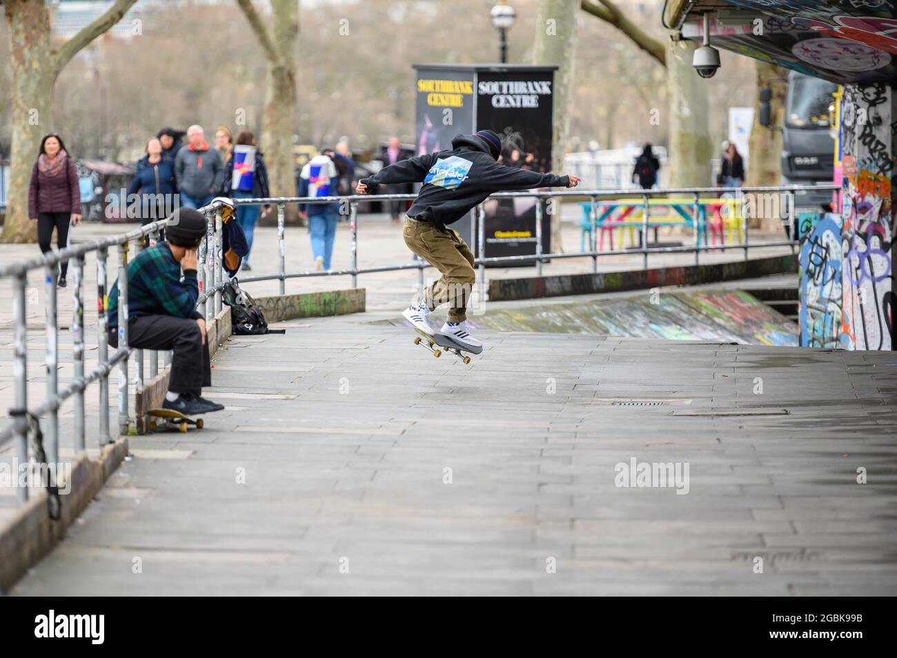 LONDON - MARCH 10, 2020: Young Skateboarder practising his moves with a friend at skate centre on London's South Bank Stock Photo