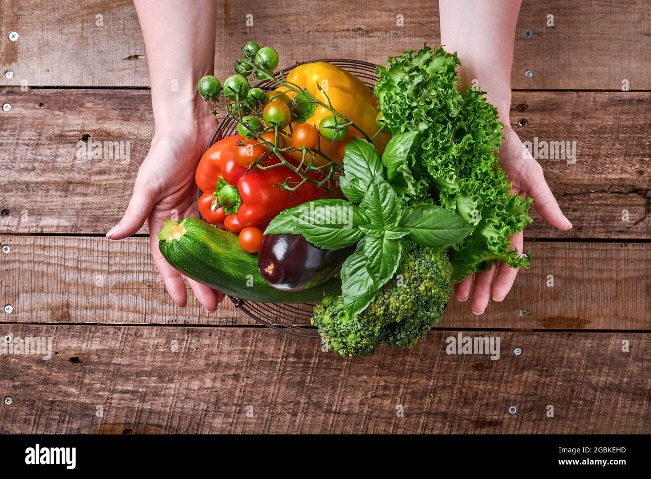 Female hand holding a basket with fresh vegetables and fruits on old ...