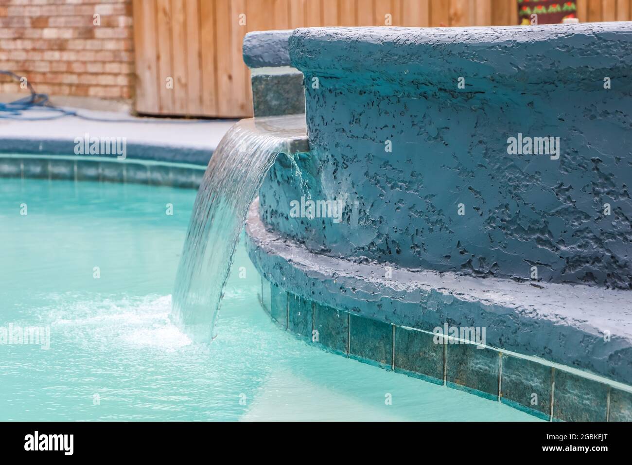 A jacuzzi hot tub next to a large freeform swimming pool with a waterfall water feature running Stock Photo