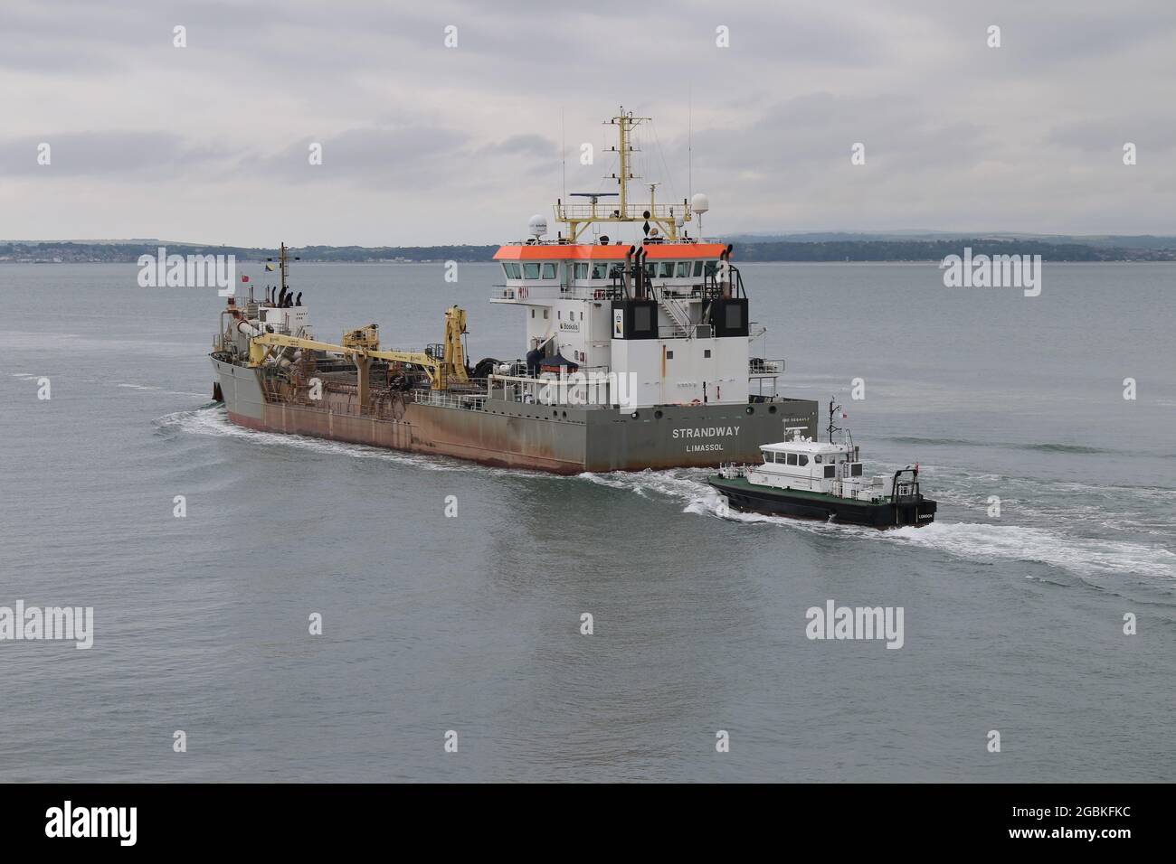 The Admiralty pilot boat SOLENT SPIRIT close to the stern of the Cypriot registered dredger STRANDWAY as it leaves harbour Stock Photo
