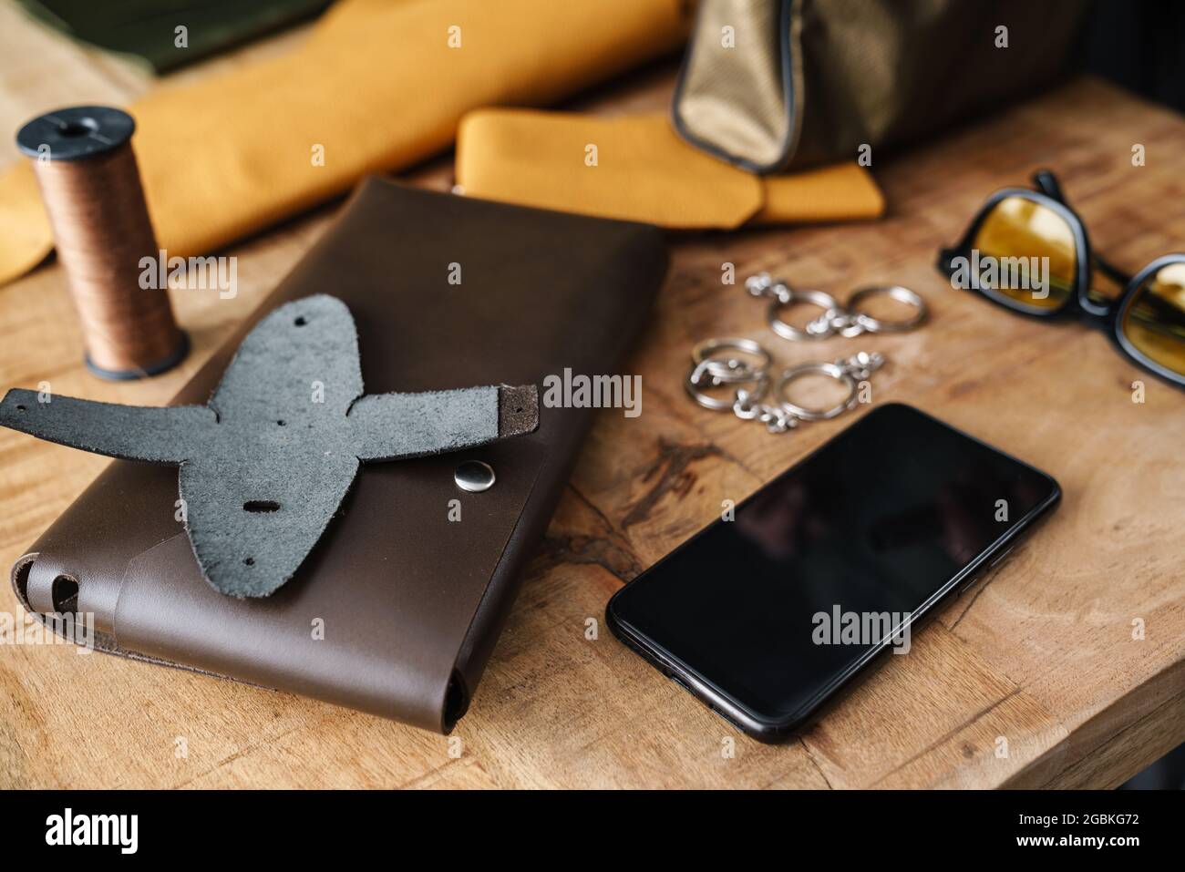 Leather bag and mobile phone on wooden table indoors Stock Photo