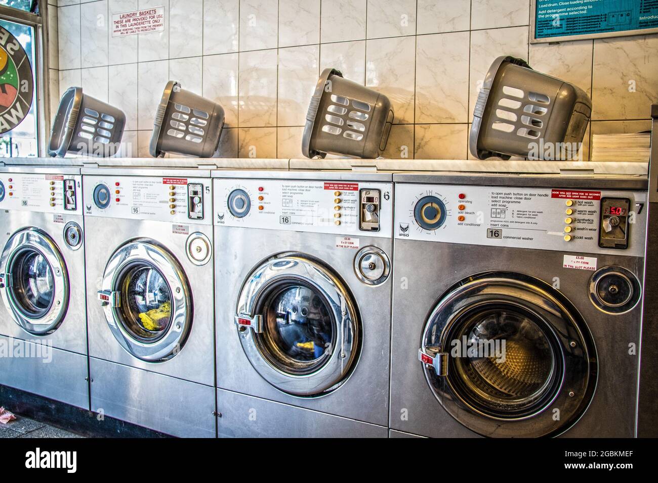 2019 07 23  Laundry or landrette  with coin  operated front loading washing machines and landry baskets on top Stock Photo
