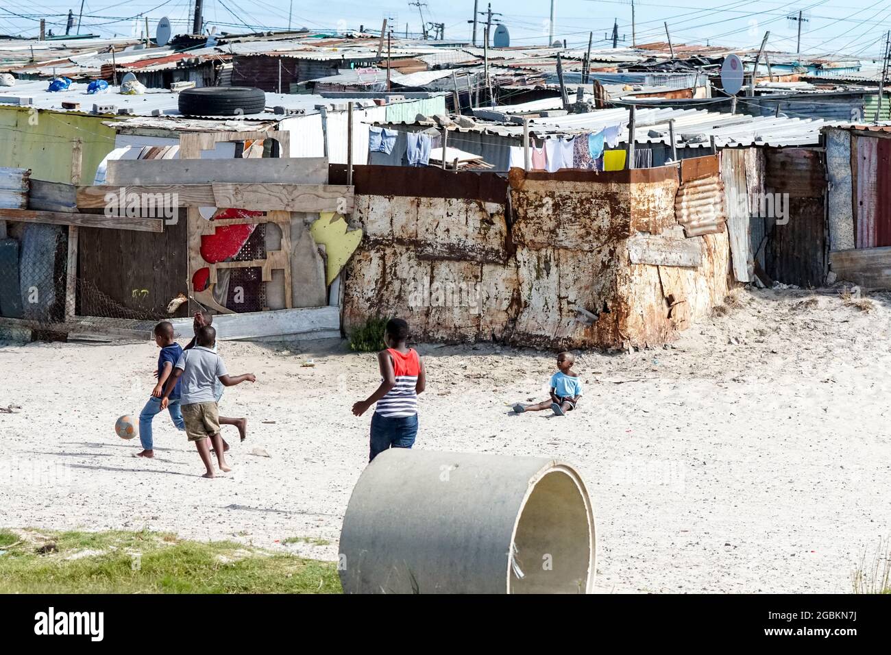 tin shacks in an African township where children play football on the sand in Cape Town, South Africa concept daily life in Africa Stock Photo