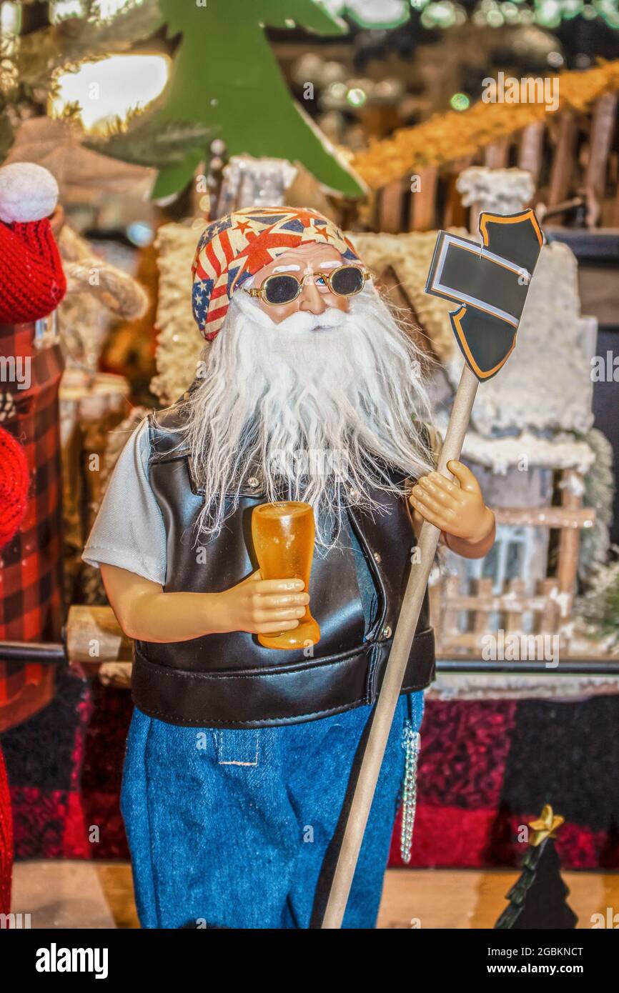Biker Santa figure with sunglasses and a beer holding sign in front of jumble of other Christmasy items Stock Photo