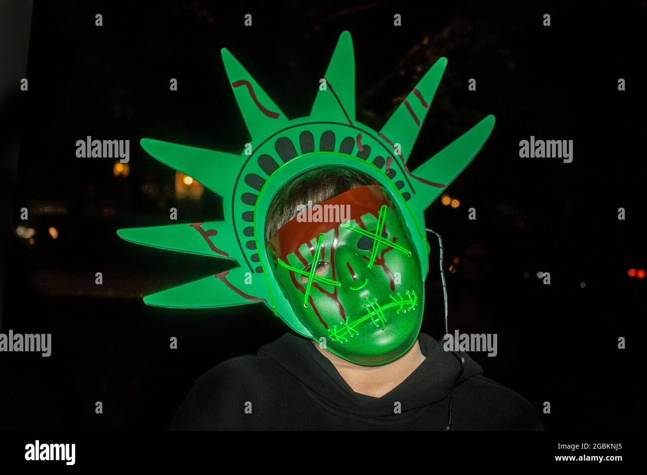 Child in Monster Statue of Liberty Halloween mask with blood dripping from it with dark background Stock Photo