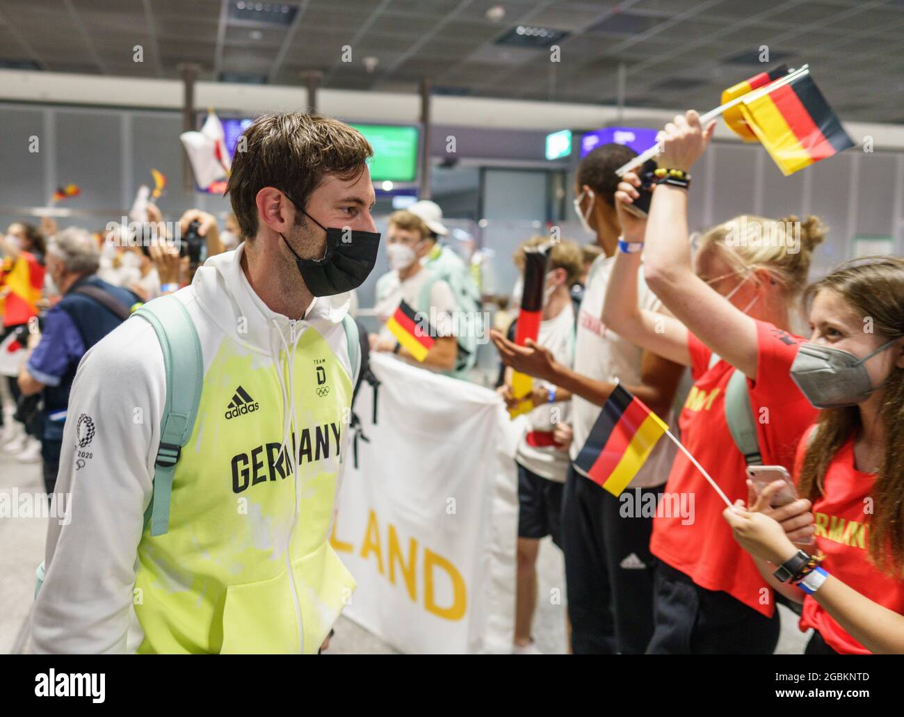 04 August 2021, Hessen, Frankfurt/Main: Handball player Uwe Gensheimer  walks past cheering youngsters at Frankfurt airport after his arrival from  Tokyo. The German national handball team was eliminated in the  quarterfinals at