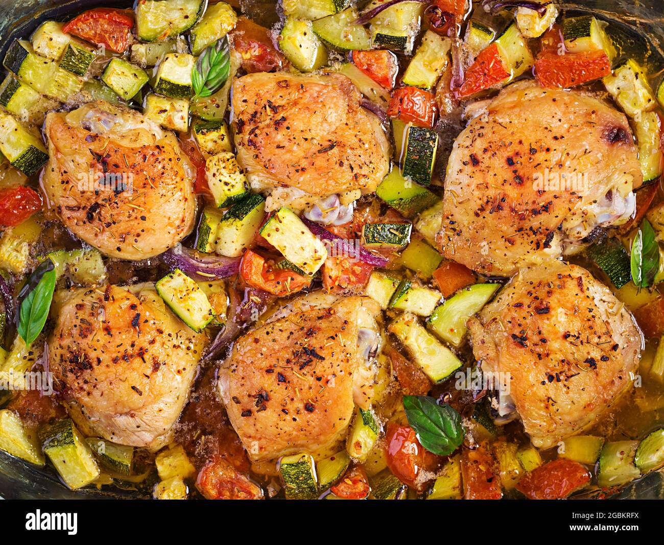 Baked chicken thighs, zucchini and vegetables in a baking dish on a