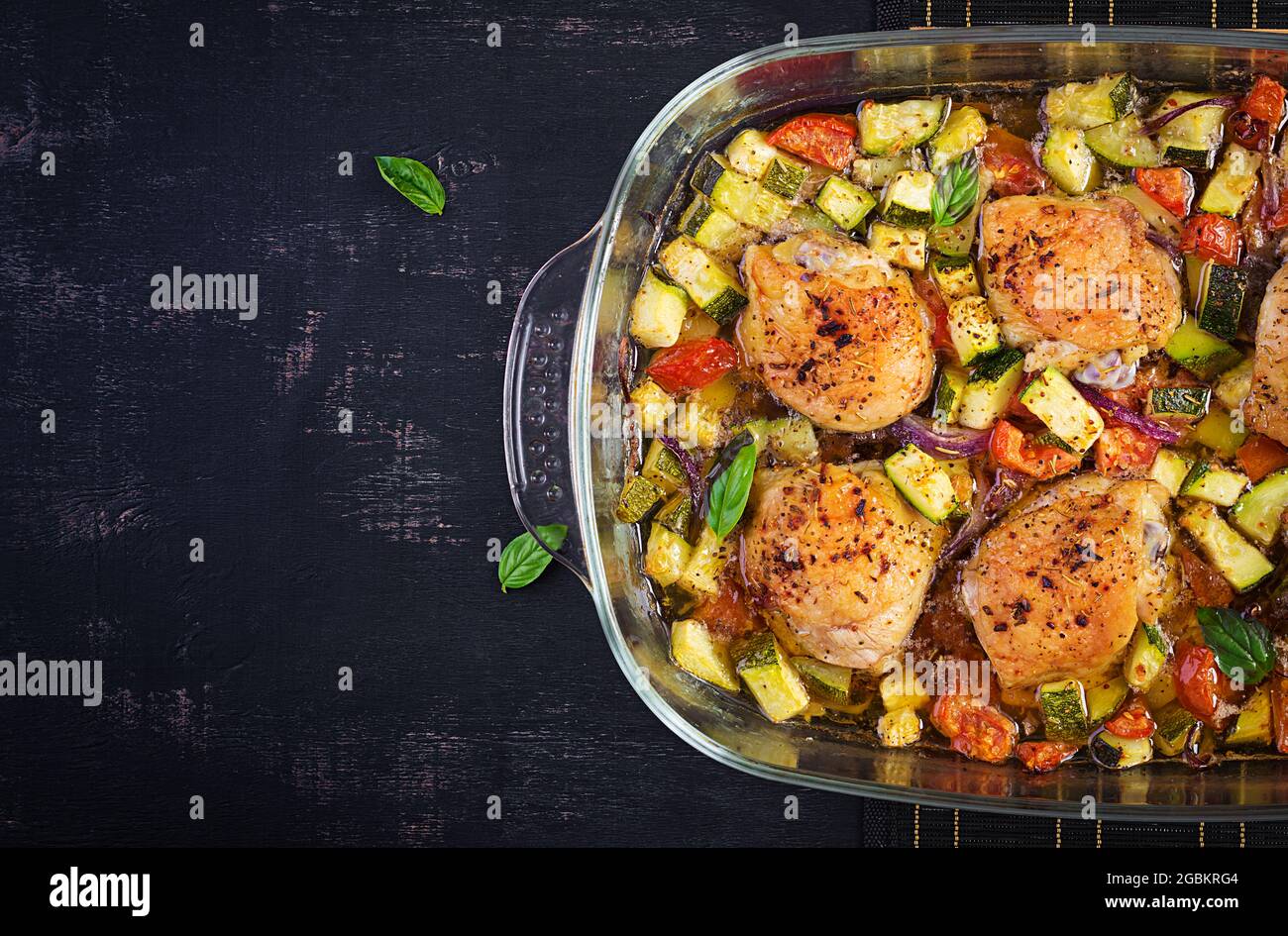 Baked chicken thighs, zucchini and vegetables in a baking dish on a