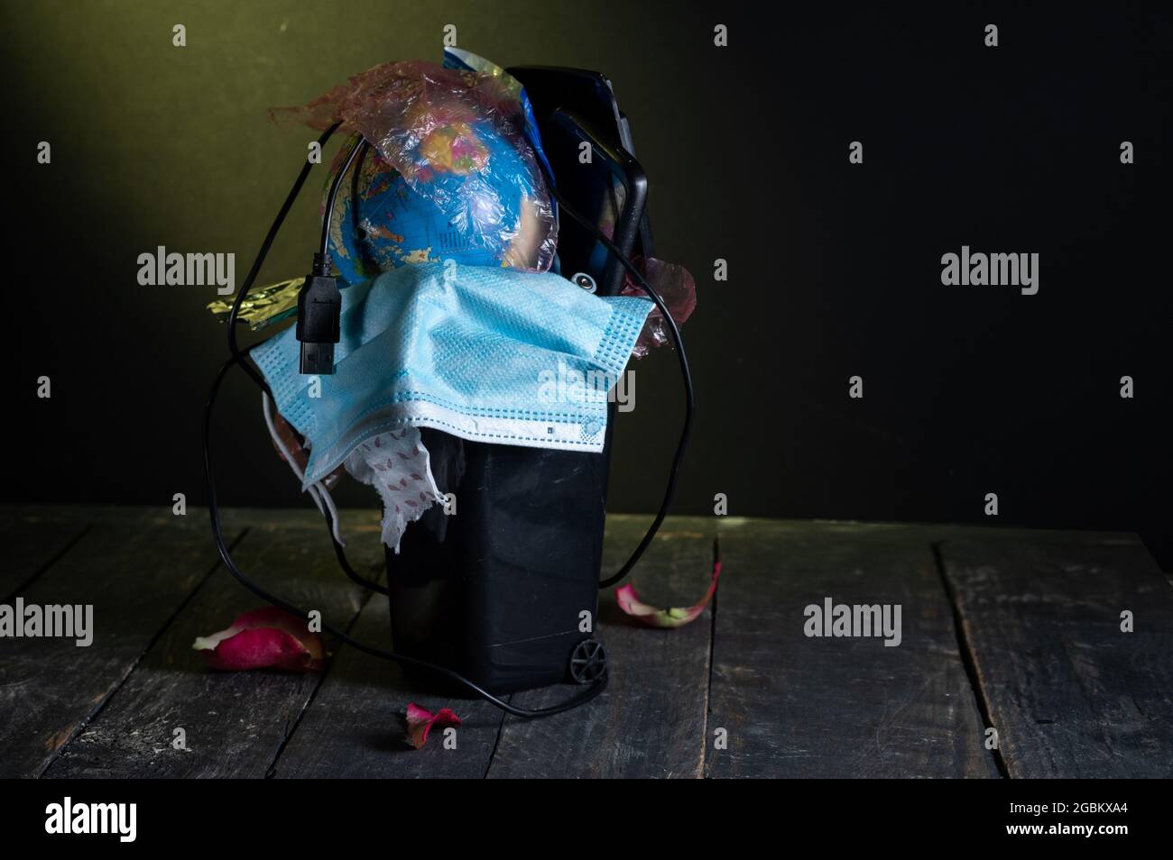 Trash can filled. A trash can with a variety of rubbish. Yellow ray of light on the trash. Stock Photo