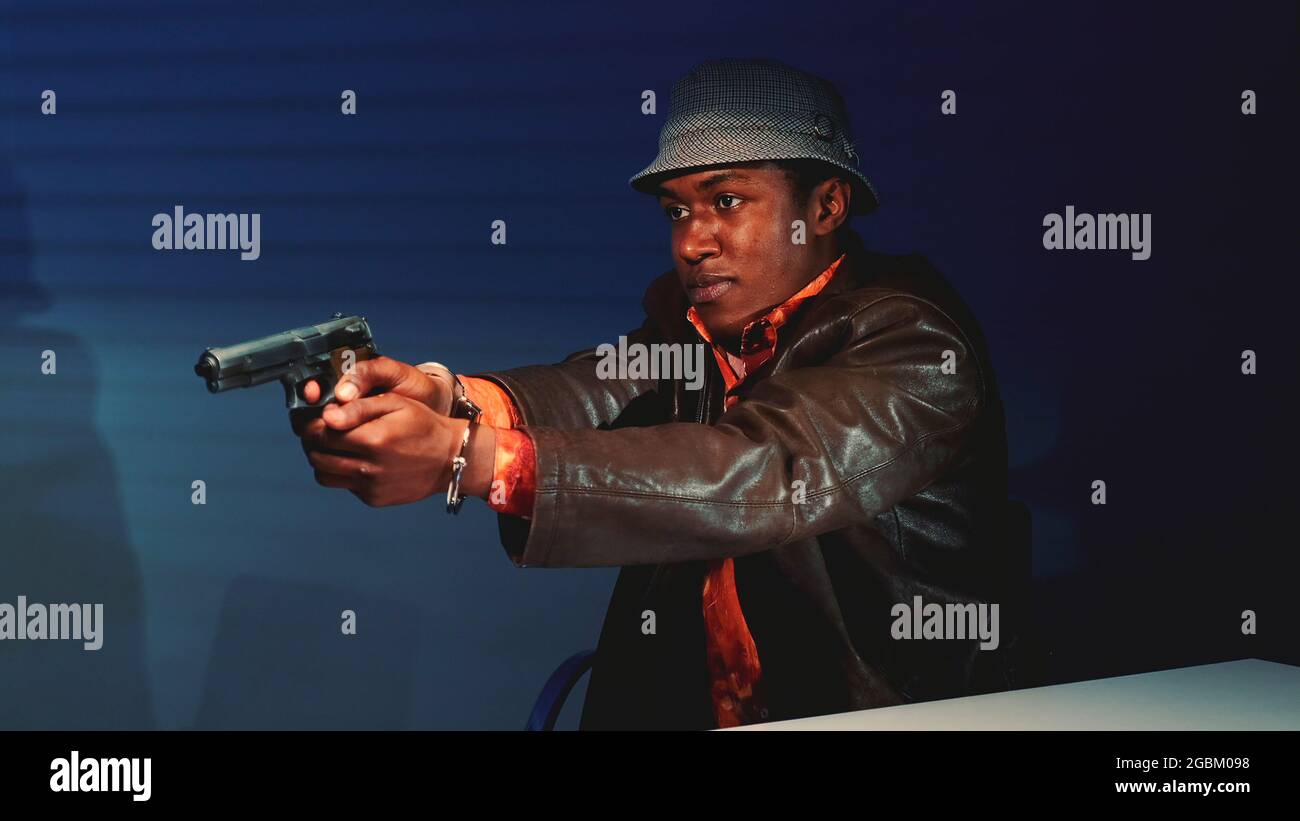 Close-up of black criminal grabbing the gun and threatening to harm cops. He trying to escape from interrogation room. Stock Photo