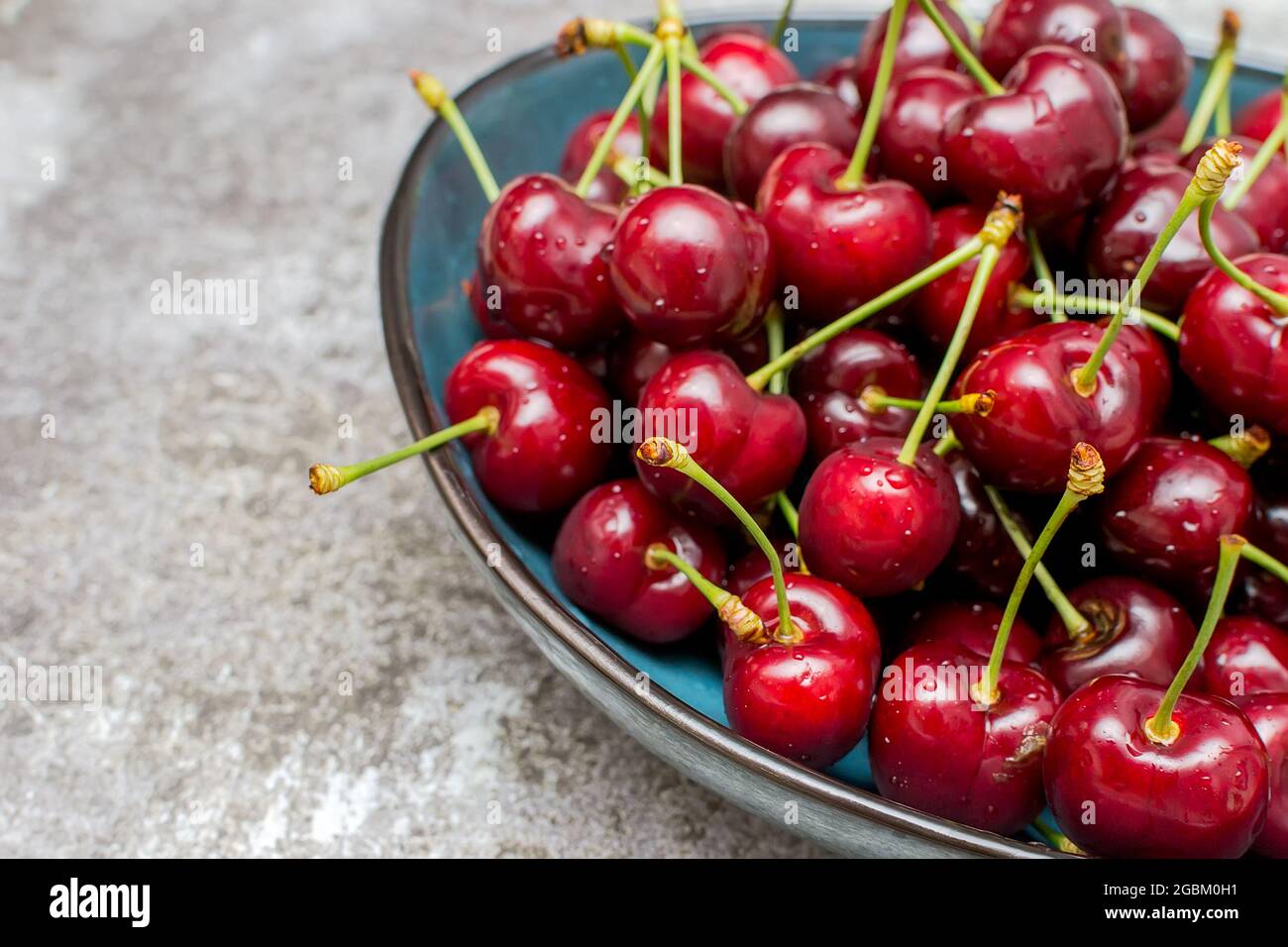 Bowl full of ripe cherries on a concrete table Stock Photo - Alamy