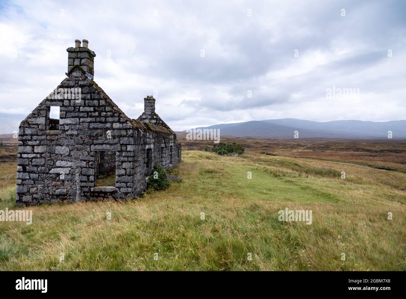 The ruined shell of a small cottage stands alone in the vast peat bog landscape of Rannoch Moor in the Highlands of Scotland. Stock Photo