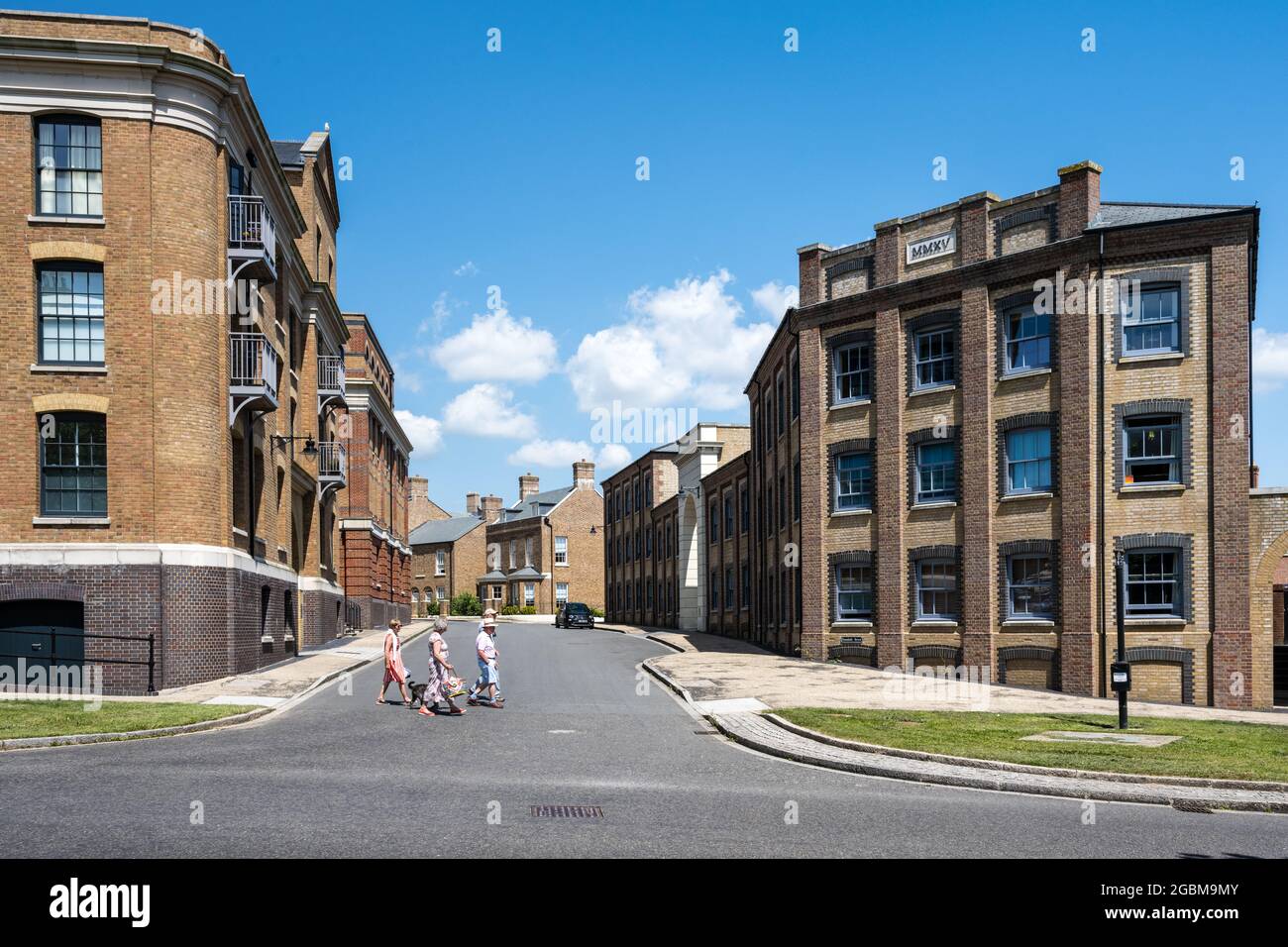 Pedestrians walk past new build houses and apartment buildings inspired by Georgian and Victorian architecture in Poundbury new town in Dorset. Stock Photo