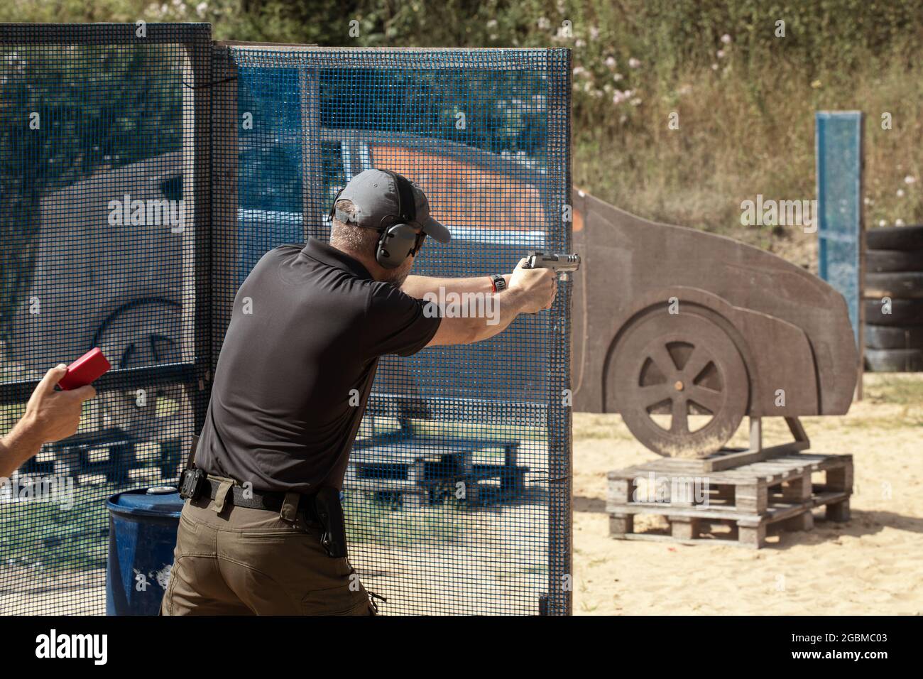 Man in tactical clothes shooting from a pistol, reloading the gun and aiming at the target in