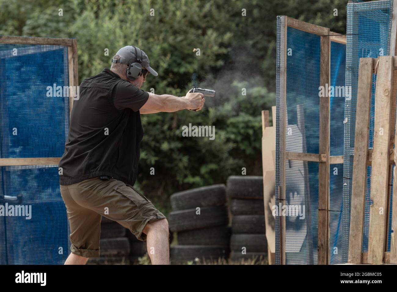 Man in tactical clothes shooting from a pistol, reloading the gun and aiming at the target in
