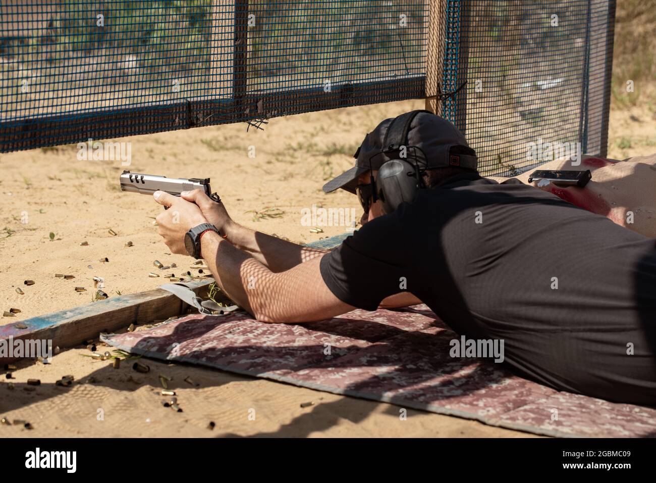 Man in tactical clothes shooting from a pistol, reloading the gun and aiming at the target in