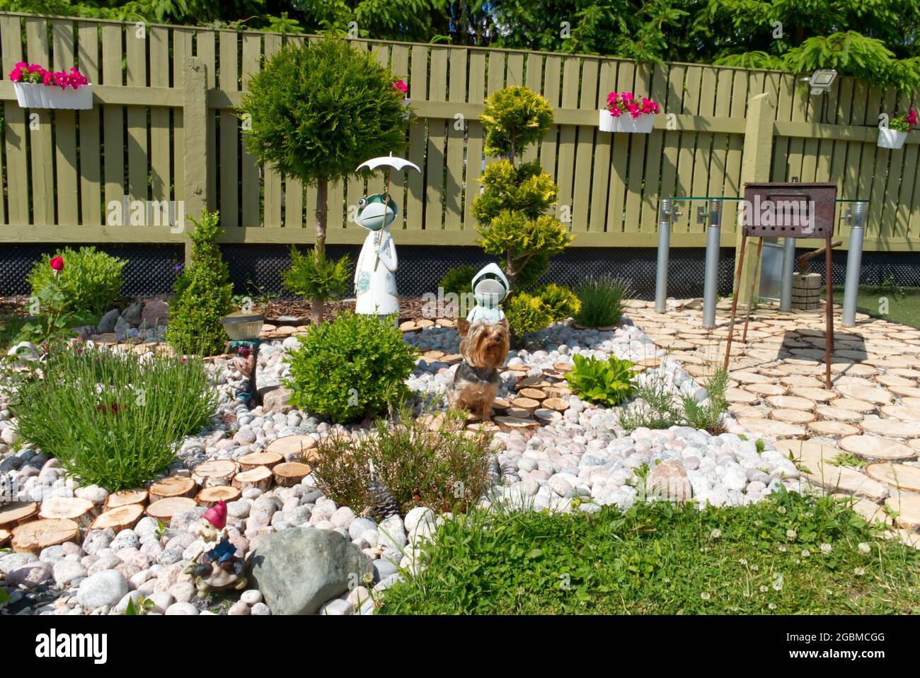 picture of nice backyard in own house at summer time. Flowers, trees and statuettes with cozy design Stock Photo