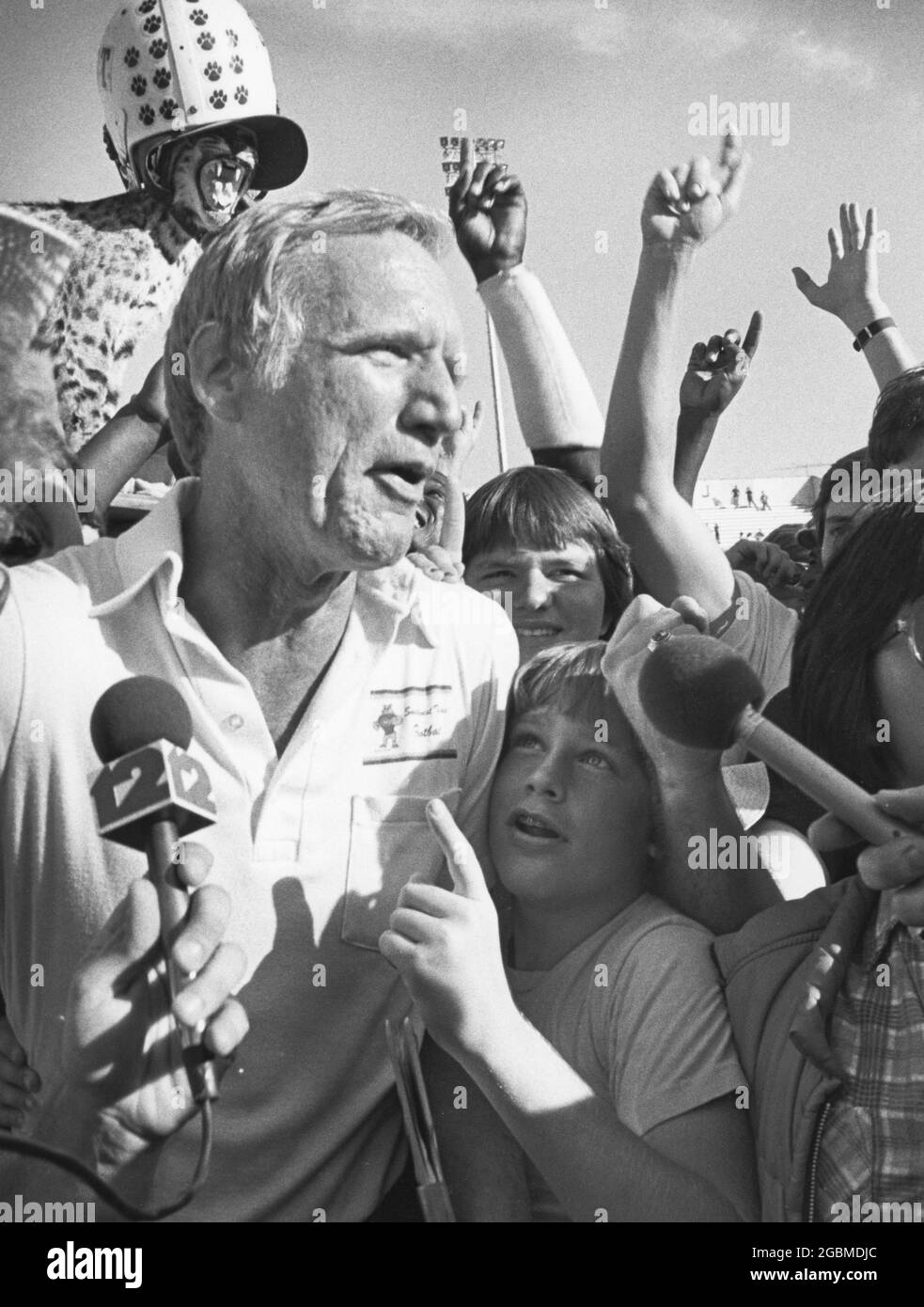 San Marcos Texas USA, circa 1982: Southwest Texas State University football coach Jim Wacker, surrounded by excited fans, talks to reporters on the field after a victory. ©Bob Daemmrich Stock Photo