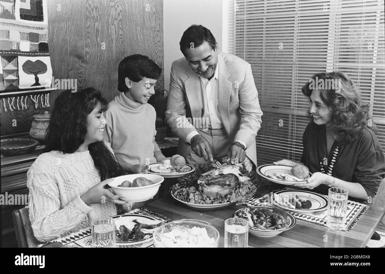 Austin Texas USA, 1990: Hispanic family enjoying Sunday dinner at their home; father carves turkey. MR ES-0506 color available. ©Bob Daemmrich Stock Photo