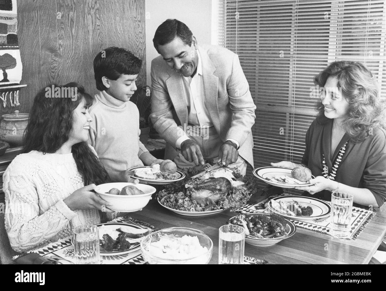 Austin Texas USA, 1990: Hispanic family enjoying Sunday dinner at their home; father carves turkey. MR ES-0506 color available. ©Bob Daemmrich Stock Photo