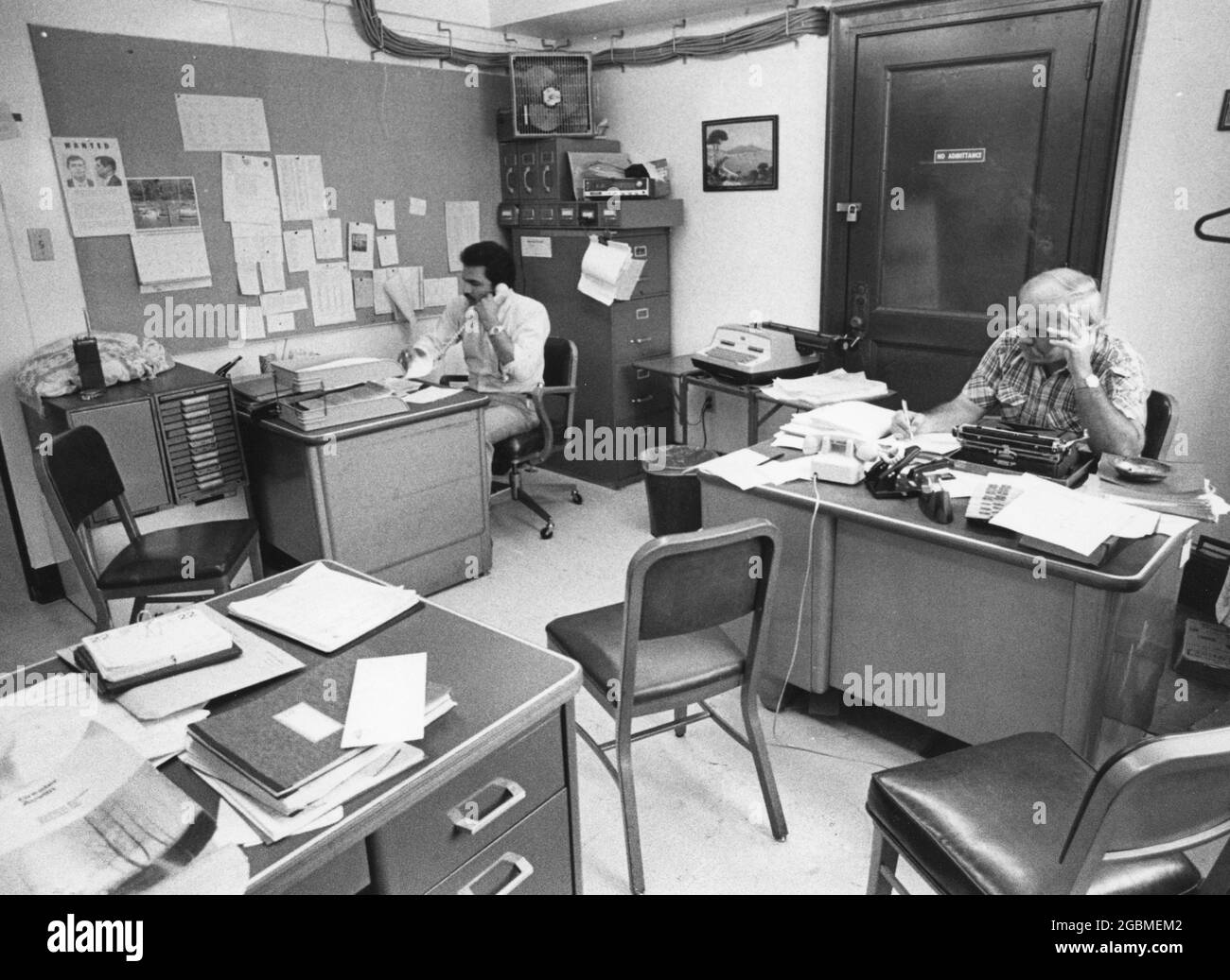 Austin Texas USA, circa 1982: Male employees crammed into small office  show crowded working conditions at the Travis County Sheriff's Office. ©Bob Daemmrich Stock Photo