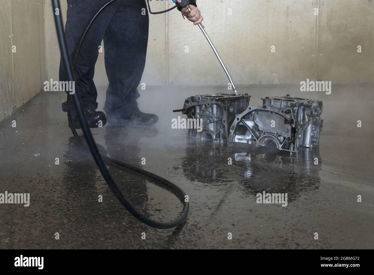 Man cleaning engine block with a power washer at the car wash Stock