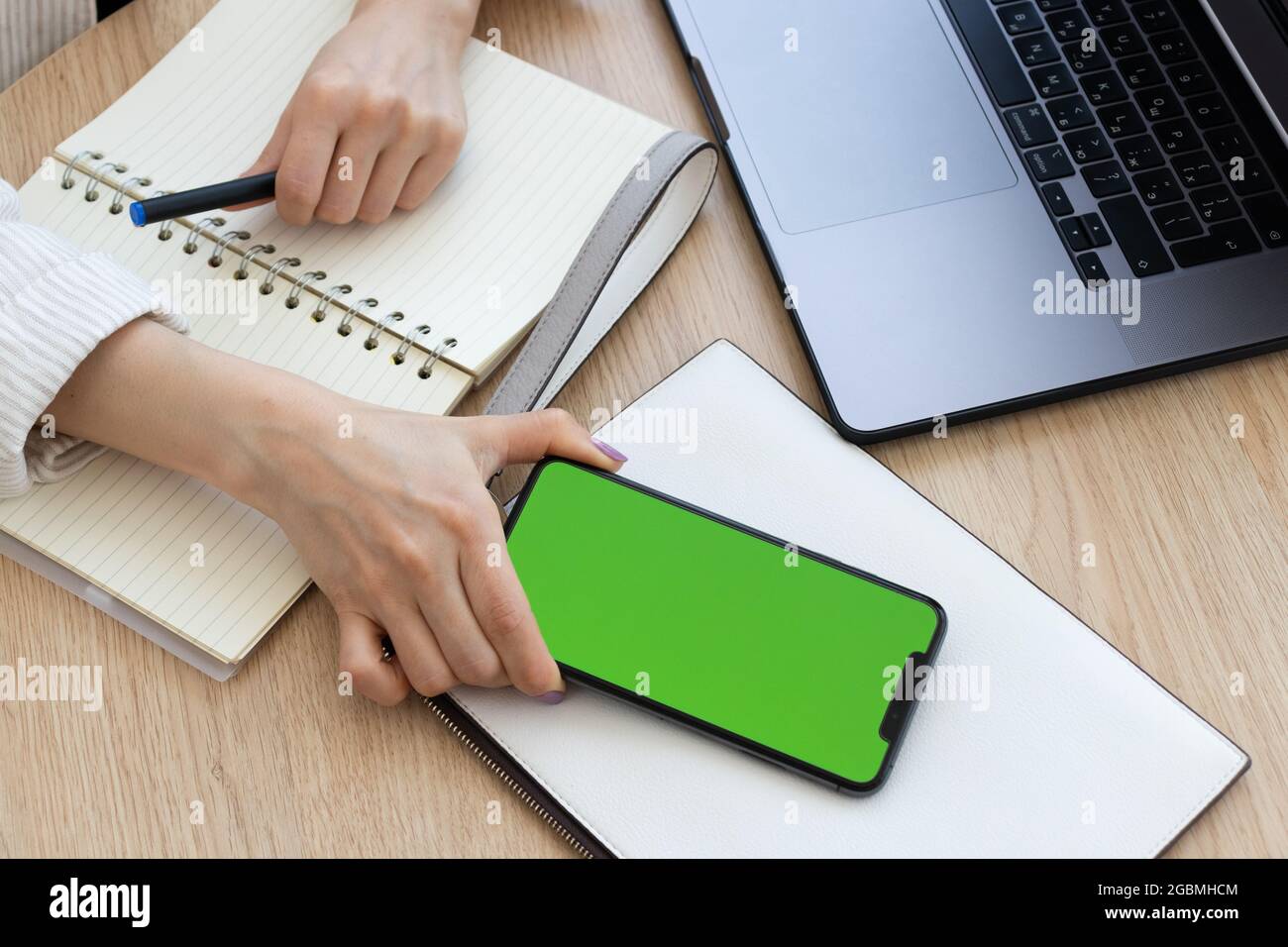 Female hand holding telephone with green screen. Stock Photo