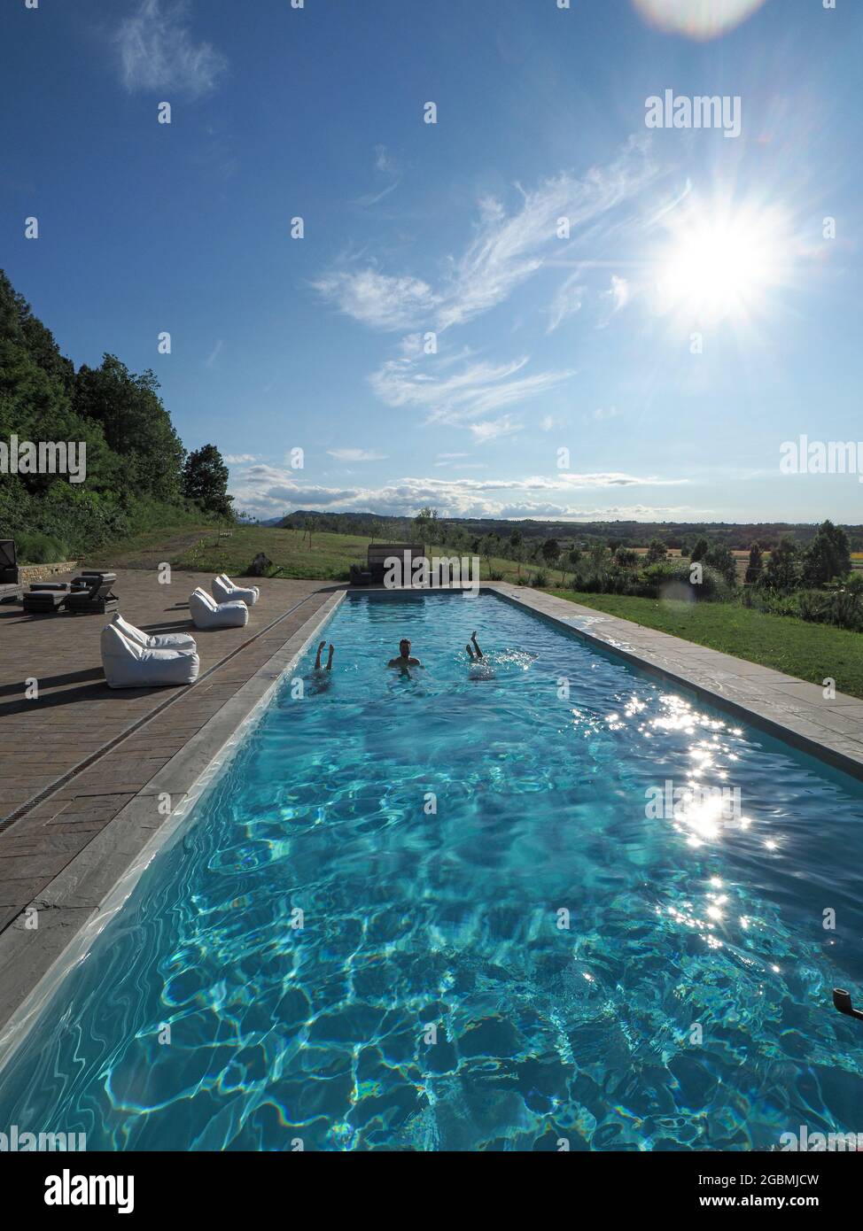 Vertical shot of a Caucasian man in the pool with two upside-down women ...