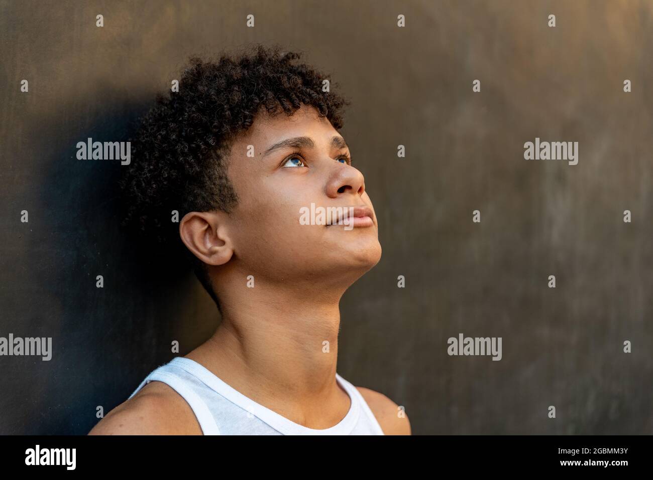 Afro latin male teenager against a wall, looking up. Stock Photo