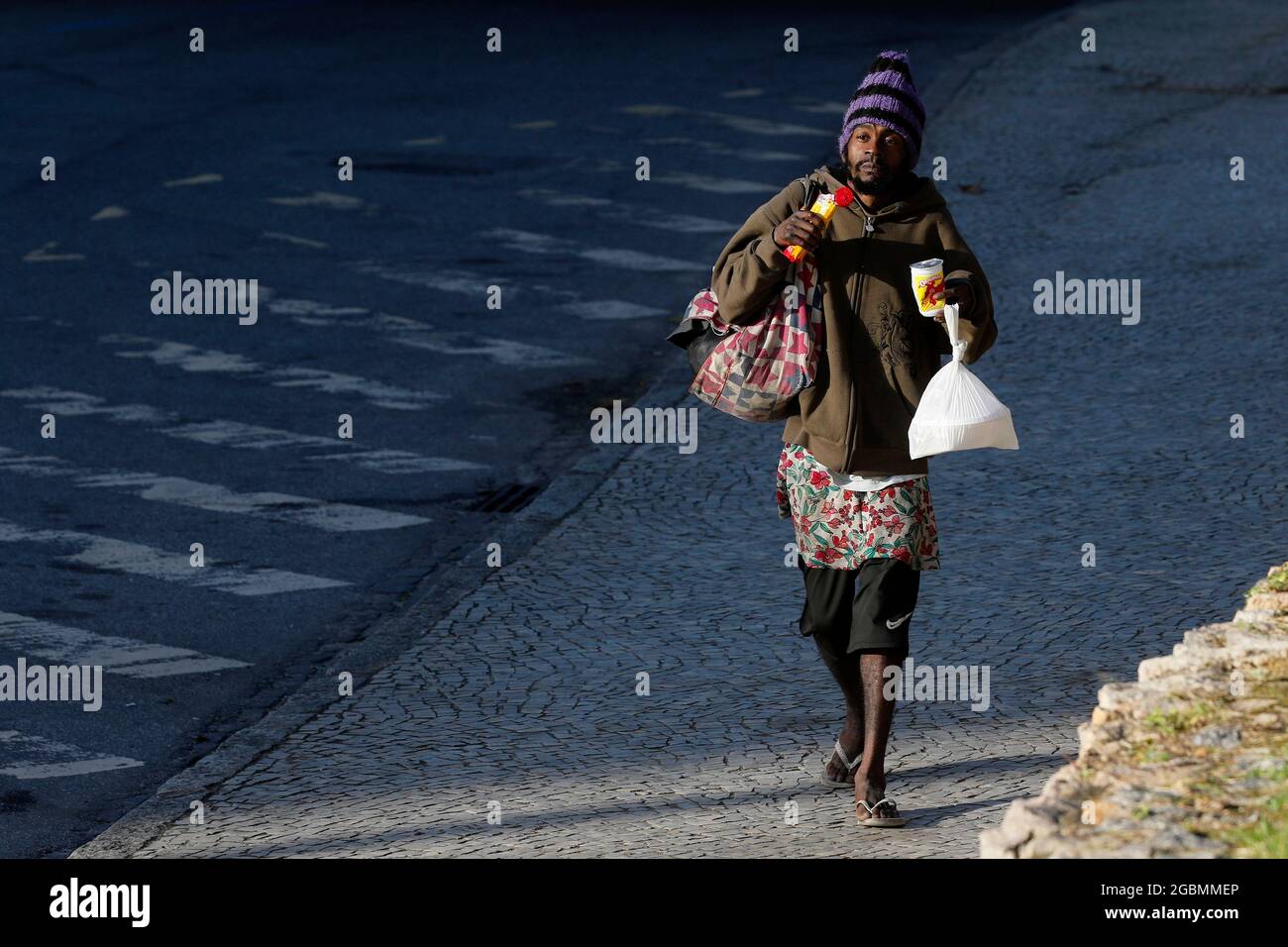 Homeless man, beggar living on a sidewalk during economic crisis at downtown, seeking help, hungry. Poverty vulnerable situation, social issues in lat Stock Photo