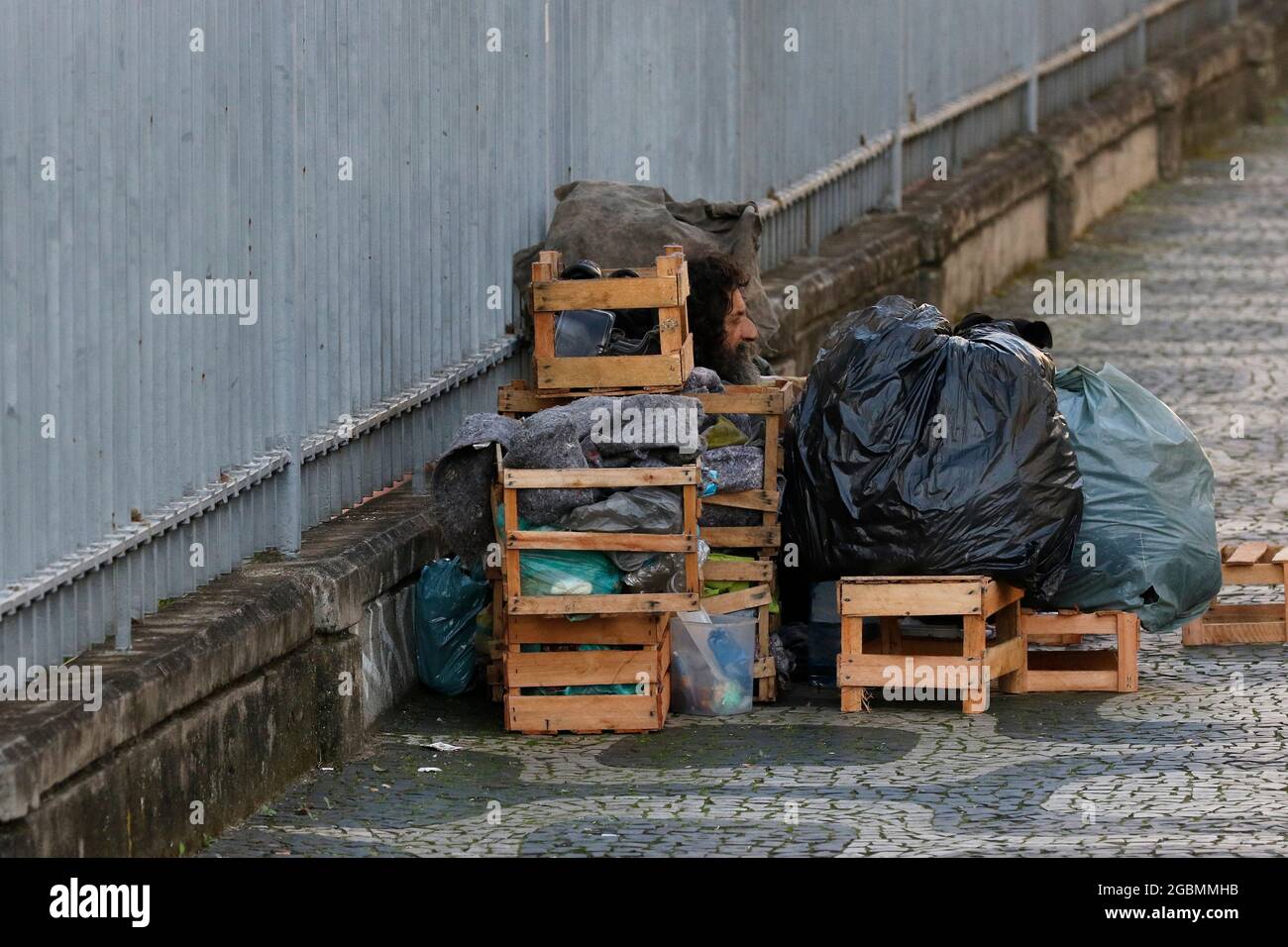 Homeless man, beggar living on a sidewalk during economic crisis at downtown, seeking help, hungry. Poverty vulnerable situation, social issues in lat Stock Photo