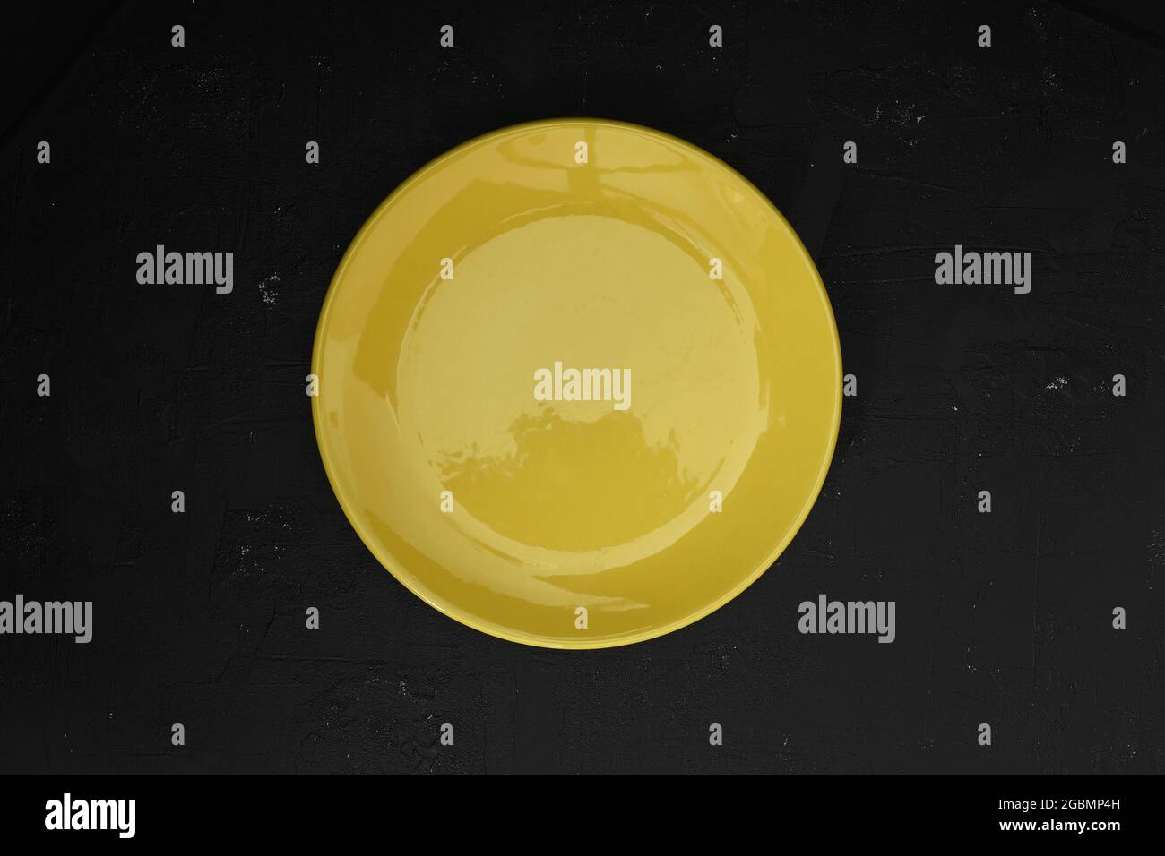 Empty yellow slate plate on dark stone table. Food background for menu ...