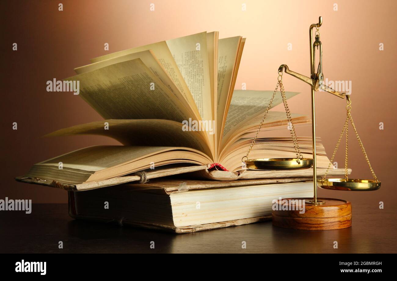 Gold scales of justice and books on brown background Stock Photo - Alamy