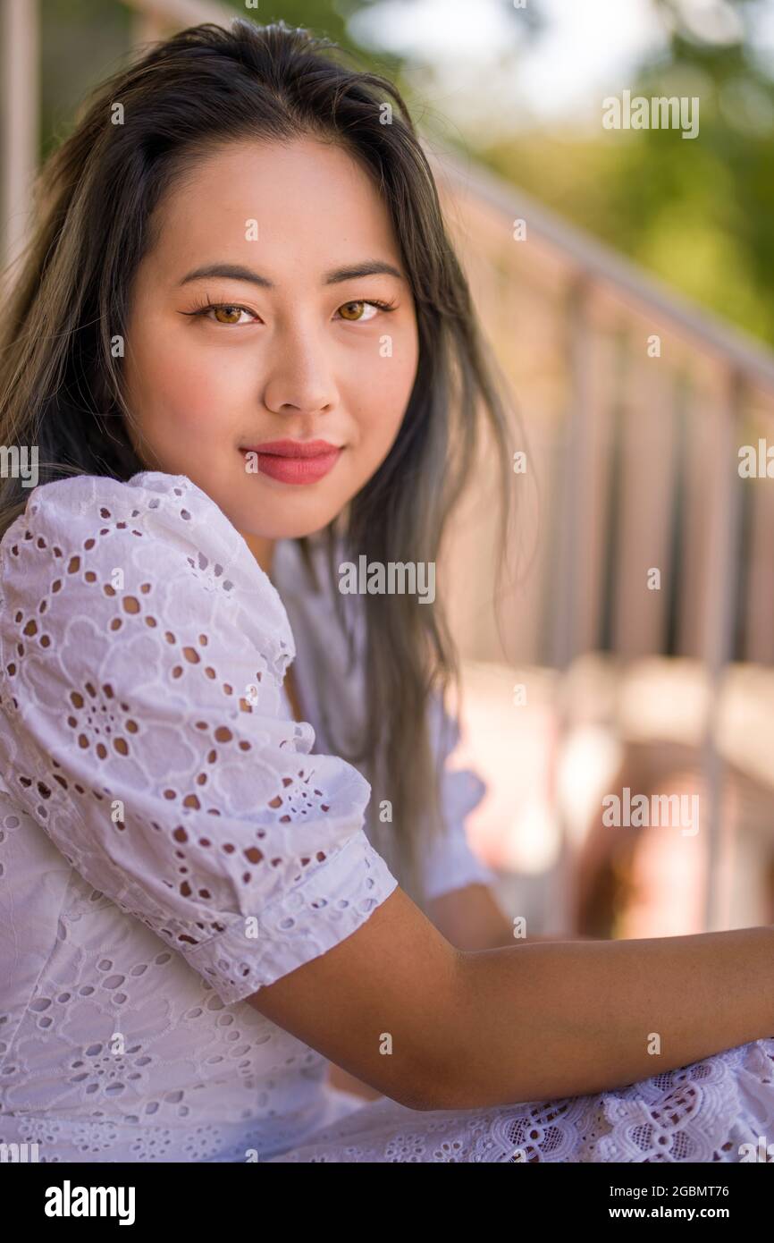 Portrait of a Young Asian Woman in a White Summer Dress Seated on Staircase Stock Photo